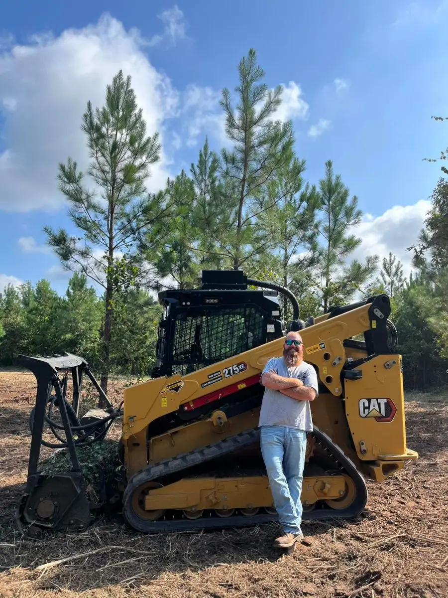 Matt Padgett of Land Pros Land Management standing beside his CAT 275 XE track loader with a forestry mulching head